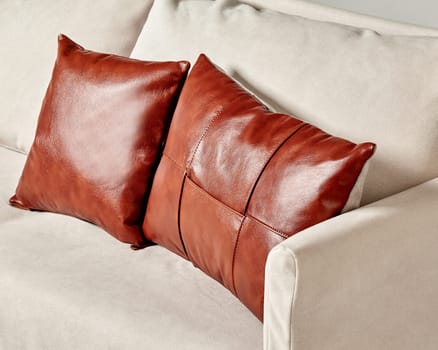Brown leather cushions add a touch of elegance to a beige sofa, creating a cozy and stylish living room atmosphere