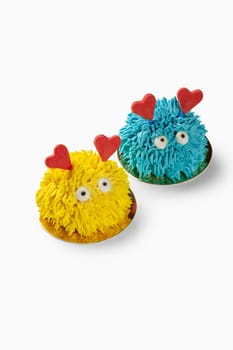 Two small colorful cakes decorated with hearts and frosting, perfect for a valentine's day celebration
