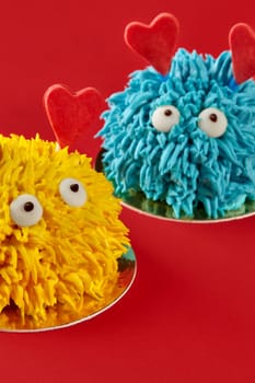 Two funny monster cakes with heart-shaped decorations are showing love and celebrating valentine's day