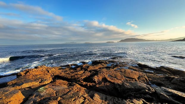 A truly breathtaking view of the rocky coastline gracefully meeting the vast ocean beneath a vibrant sky