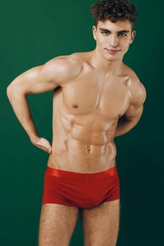 Muscular male model showcasing a toned body in red swim shorts, exuding confidence and style. Ideal for wellness and fashion themes.