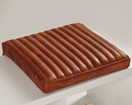 Brown leather seat cushion with vertical ribs adds a touch of rustic charm to a white bench, creating a cozy and inviting space