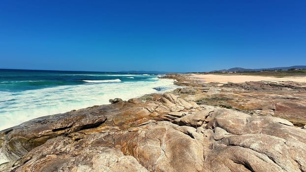 A stunning beach view showcasing magnificent rocks, beautiful turquoise water, and pristine clear skies above