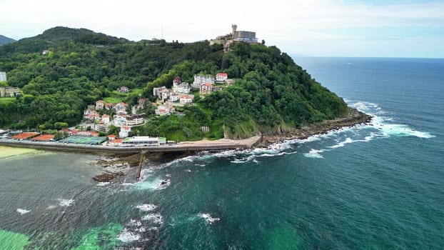Aerial shots showcase a vibrant coastal town nestled against lush hills and picturesque sandy beaches