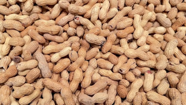 A highly detailed closeup view showcasing numerous raw, shelled peanuts that are scattered across a flat surface area