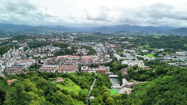 Experience a stunning aerial view of a lively coastal city, framed by majestic mountains in the background