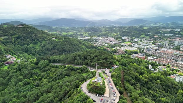 This stunning aerial shot beautifully showcases a vibrant city nestled amidst lush greenery and gentle rolling hills