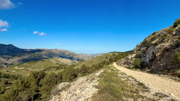 A breathtaking view from the hillside showcases the rolling green landscapes lying beneath a clear blue sky