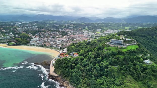 A stunning aerial photo captures a coastal town amid lush hills, a pristine beach, and gentle ocean waves