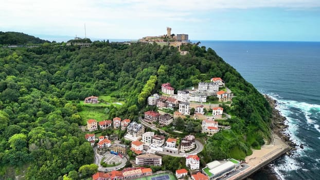 Aerial view showcases a charming coastal village, surrounded by vibrant greenery and the shimmering ocean