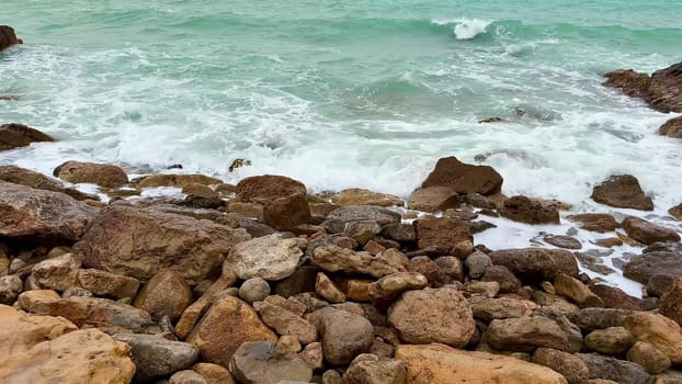 Dynamic waves continuously interact with rocks and boulders along a calm and tranquil coastal environment