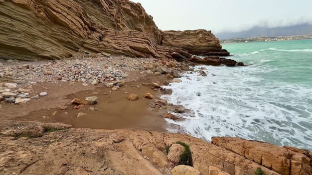 A truly beautiful rocky beach featuring crashing waves and stunning turquoise waters on a serene sunny day
