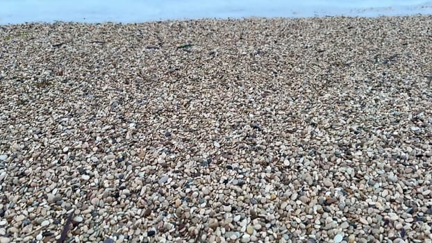 A tranquil beach scene featuring waves softly lapping a picturesque pebble shoreline beneath the gentle evening light