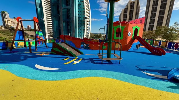 A vibrant and colorful playground featuring various slides and swings, set against a modern city backdrop