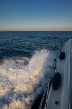 Sailboat navigating through calm waters of Greece, creating waves and splashes, showcasing beautiful blue seascape under clear sky, ideal for travel adventures.