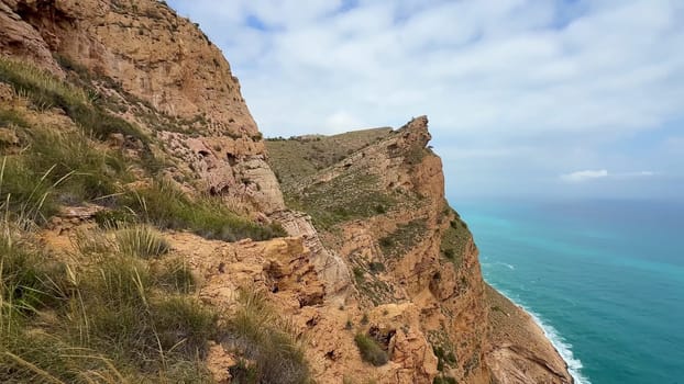 Experience the stunning view of vibrant turquoise waters perfectly set against dramatic cliffs beneath a cloudy sky