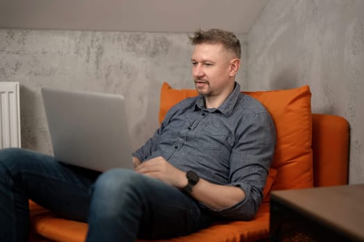 Handsome Man Sitting In Chair With Laptop At Home