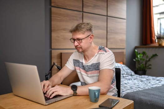 Man Working Remotely On Laptop At Home In Bedroom