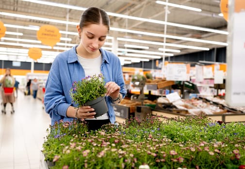 Girl In Supermarket Choosing Potted Flowers In The Flower Department