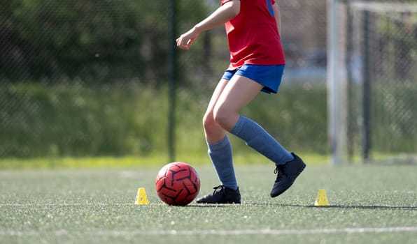 Girl Skillfully Dribbles Ball Between Flip Cups During Football Practice, Captured In Close-Up, Side View