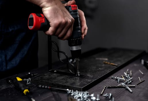 Man Screws Bracket To Shelf With Screwdriver, Hands In Close-Up