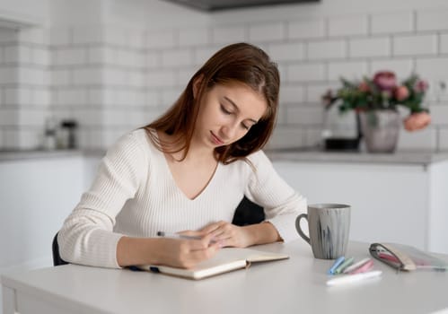 Teenage Girl Writing In Journal At Home