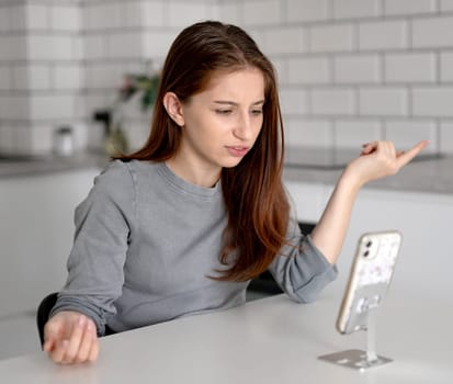 Unhappy Teen Girl Looking At Smartphone At Home