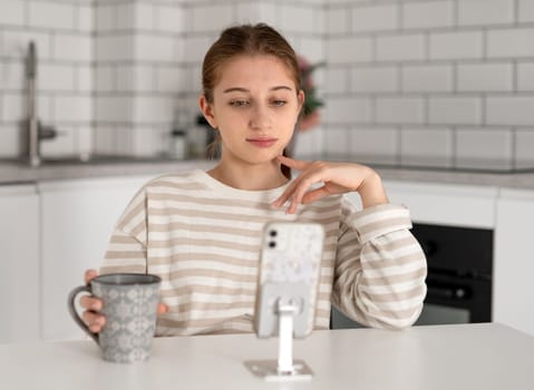 Unhappy Teen Girl Looking At Smartphone At Home