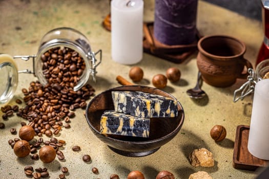 Two slices of marble cheese nestled in a wooden bowl, surrounded by coffee beans, macadamia nuts, candles, and brown sugar, creating a cozy atmosphere