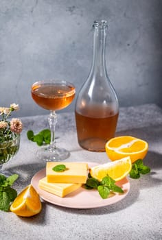 Gourmet cheese slices paired with fresh orange and mint on a pink plate, complemented by a glass and bottle of rose wine