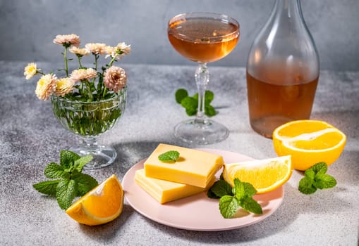 Gourmet orange flavored cheese paired with orange slices, mint, and rose wine, accented by a bouquet of flowers