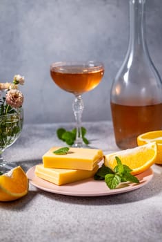 Gourmet white chocolate bars infused with orange zest, served with rose wine, fresh mint, and orange slices, creating a luxurious and refreshing treat