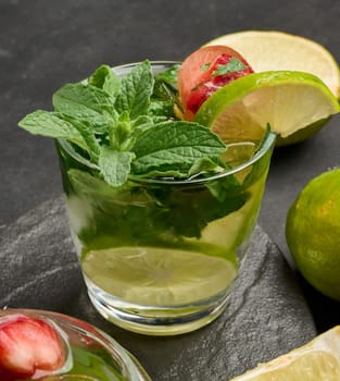 Refreshing mojito cocktail with lime, mint, strawberry, and ice on dark background, top view