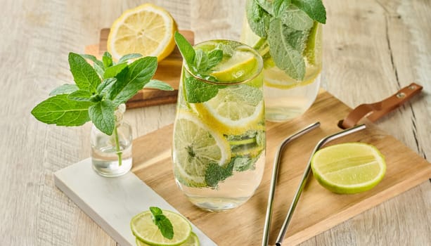 Refreshing citrus and mint drink in glasses with ice, lemon, lime, and mint leaves. Healthy summer beverage