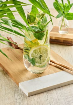Refreshing citrus and mint drink in glasses with ice, lemon, lime, and mint leaves. Healthy summer beverage