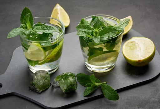 Refreshing mojito cocktail with lime, mint, and ice on dark background, top view