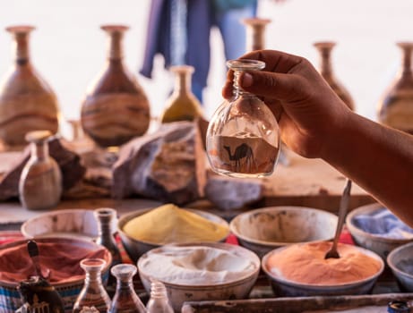 A skilled artisan meticulously crafting a colorful sand bottle souvenir in the ancient city of Petra
