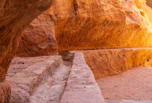 Carved water channels and pipes along the walls of the narrow gorge of the Siq entering Petra in Jordan
