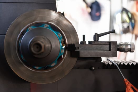 Car mechanic or serviceman disassembly and checking a disc brake and asbestos brake pads for fix and repair problem at car garage or repair shop