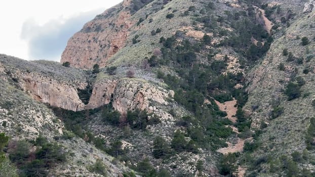 A breathtaking and picturesque view of rocky hills adorned with lush green vegetation beneath a cloudy sky