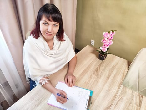 In a cozy office setting, a middle-aged psychologist engages in note-taking, focusing on patient insights and observations.