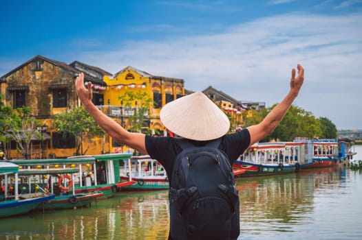 back of happy male tourist traveler in a Vietnamese hat on a bridge in old town in Hoi An in Vietnam in Asia