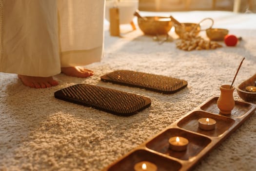 Barefoot woman preparing for nail board Sadhu meditation practice surrounded by incense, candles, and healing tools.