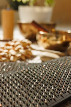 Close up of Sadhu meditation nail board in warm light on floor at home with singing bowls and meditation instruments