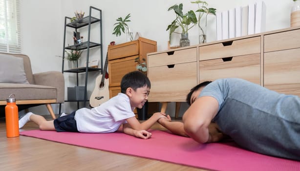A cheerful father and son enjoy a light-hearted arm wrestling match at home, enhancing their bond and making fitness fun.