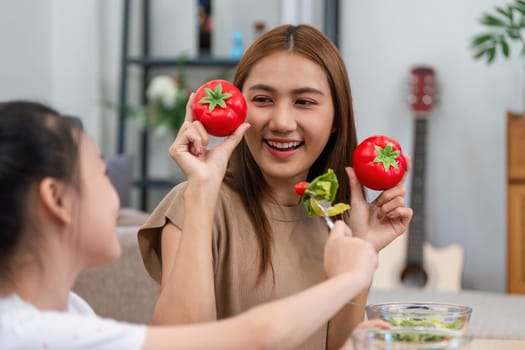 A mother and daughter joyfully enjoying fresh tomatoes, promoting wellness and healthy eating habits in their daily lives.