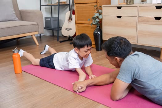 A joyful father and son engaging in a fitness activity at home, showcasing love, playfulness, and health during their workout session on an exercise mat.