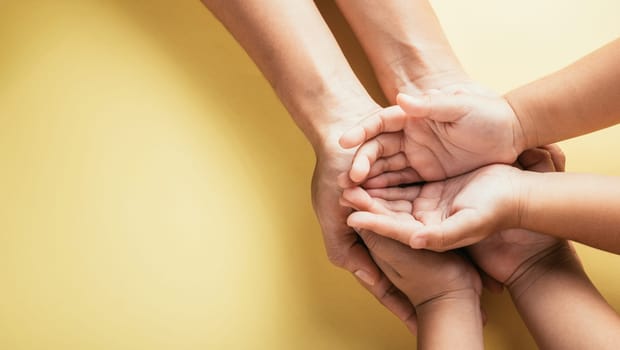 Embracing togetherness and trust, Studio shot captures top view of family hands stacked against an isolated background. Parents and kids hold an empty space symbolizing Family and Parents Day.