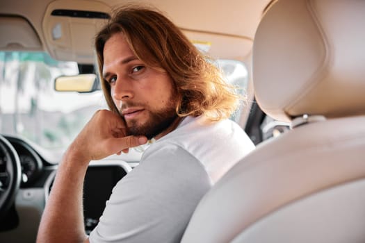 A man gazes thoughtfully over his shoulder in a car, with a soft focus on the vehicle s interior Warm tones create a reflective mood
