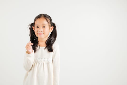 Portrait of happy Asian young kid girl, confidently smiling showing mini heart sign with finger studio shot isolated on white background. Kindergarten child expressing love and joy for Valentine's Day